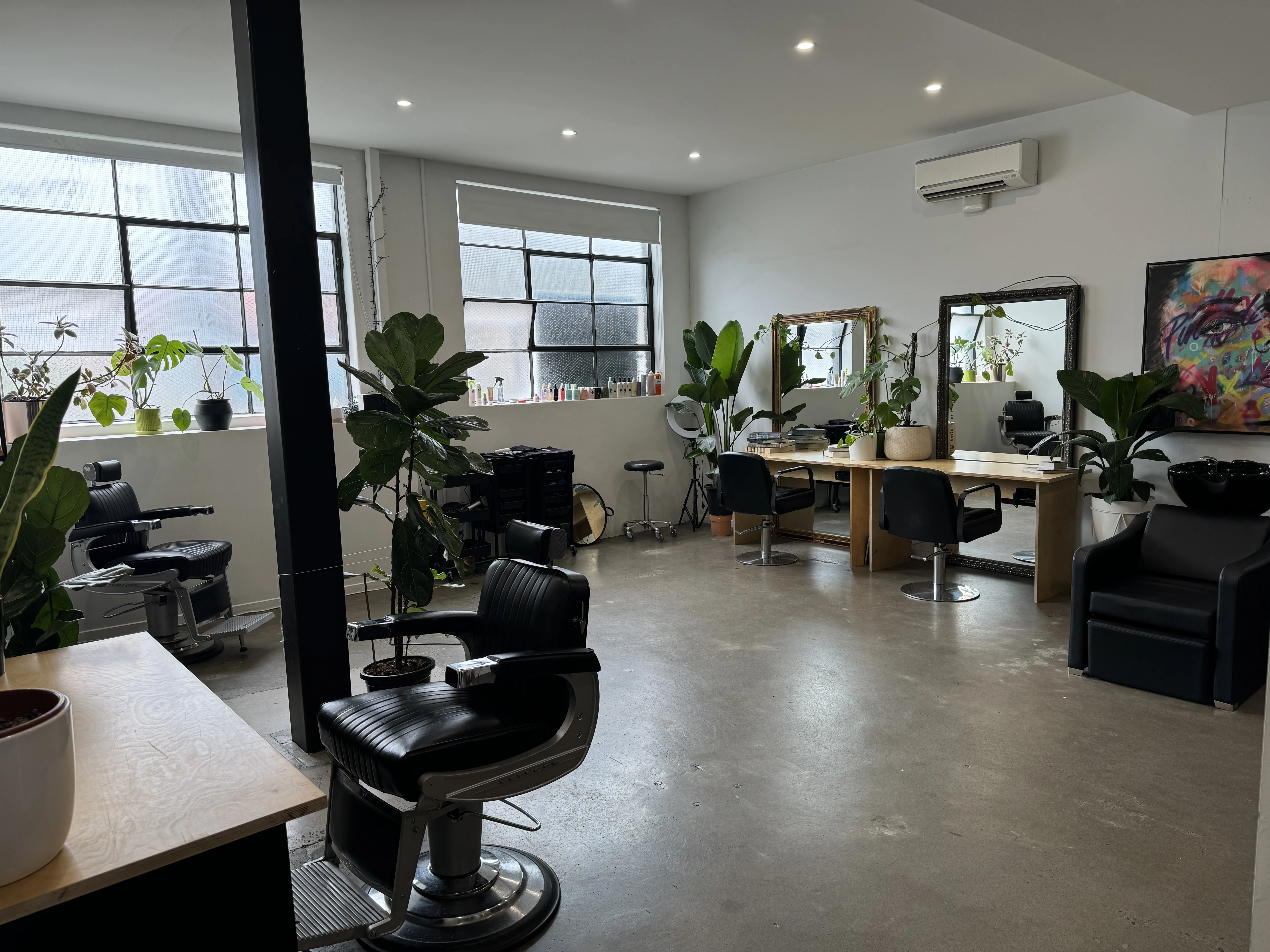 Ziyad Salon interior — the warehouse studio at 1/10 Langwells Parade Northcote, showing the row of vintage barber chairs, mirrored plywood stations, tall factory windows and graffiti wall art