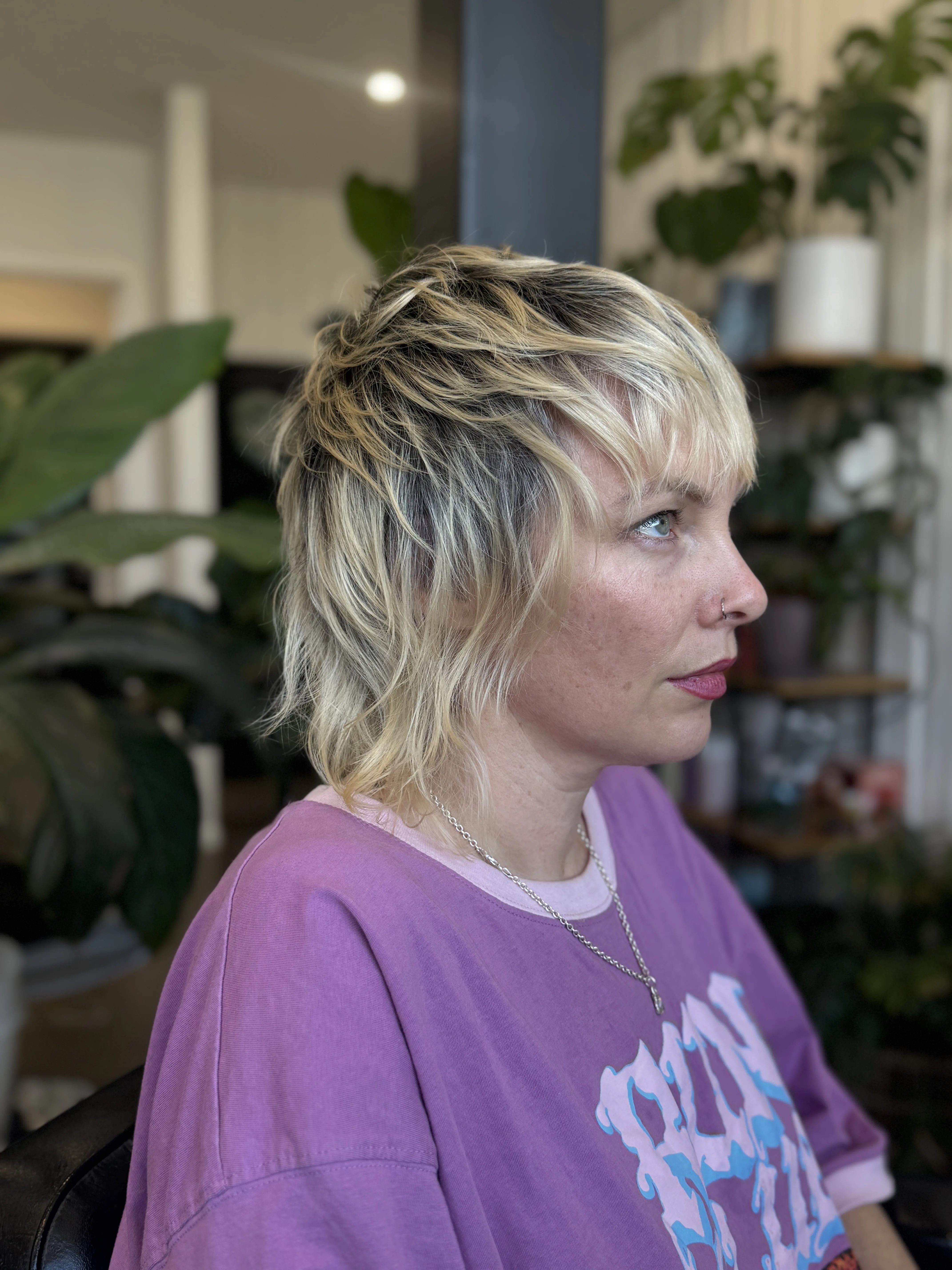 In-salon client — woman in side profile, blonde textured shag with bangs, nose ring