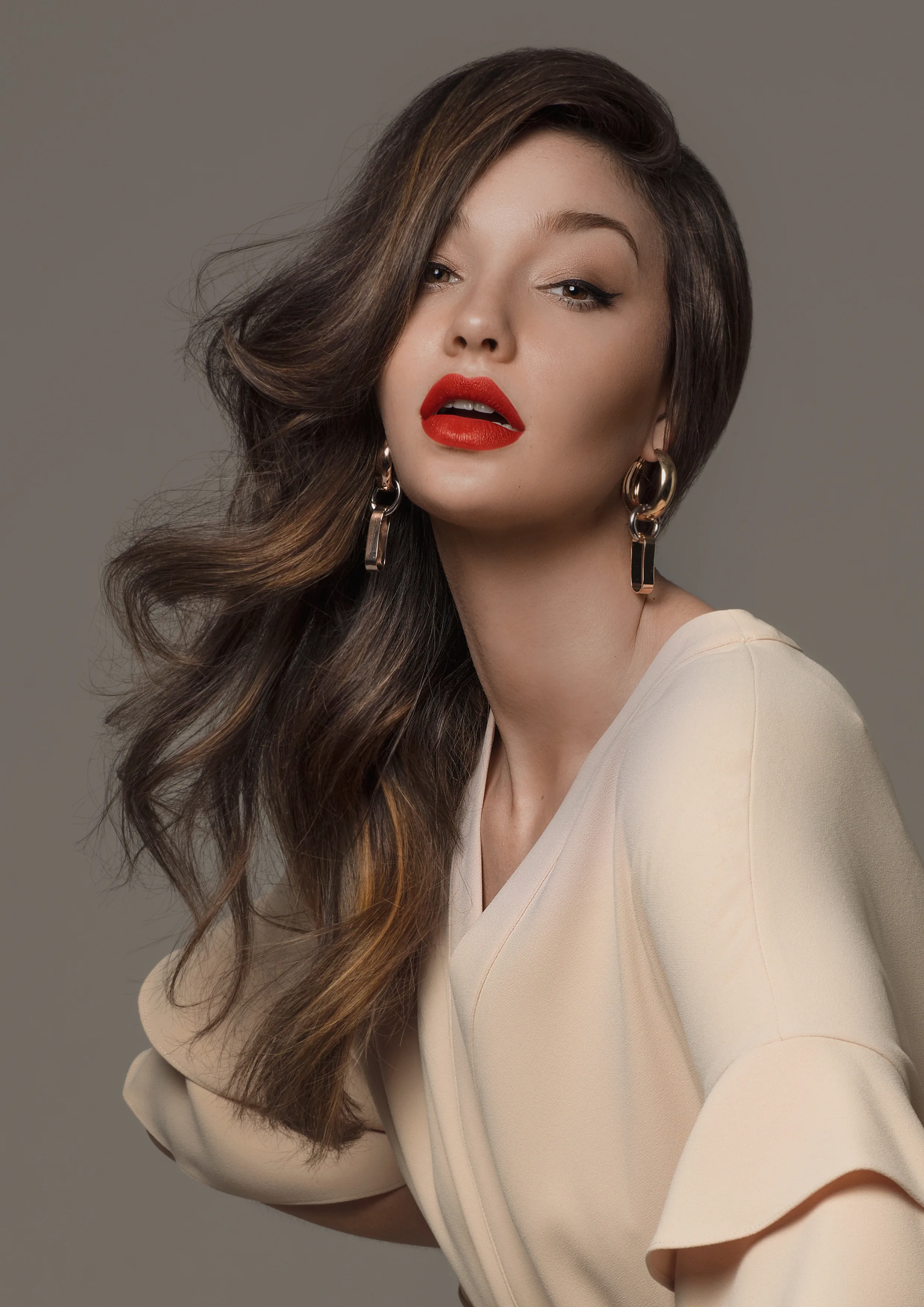 Editorial — woman, long glossy brunette waves with caramel highlights, bold red lip, cream blouse